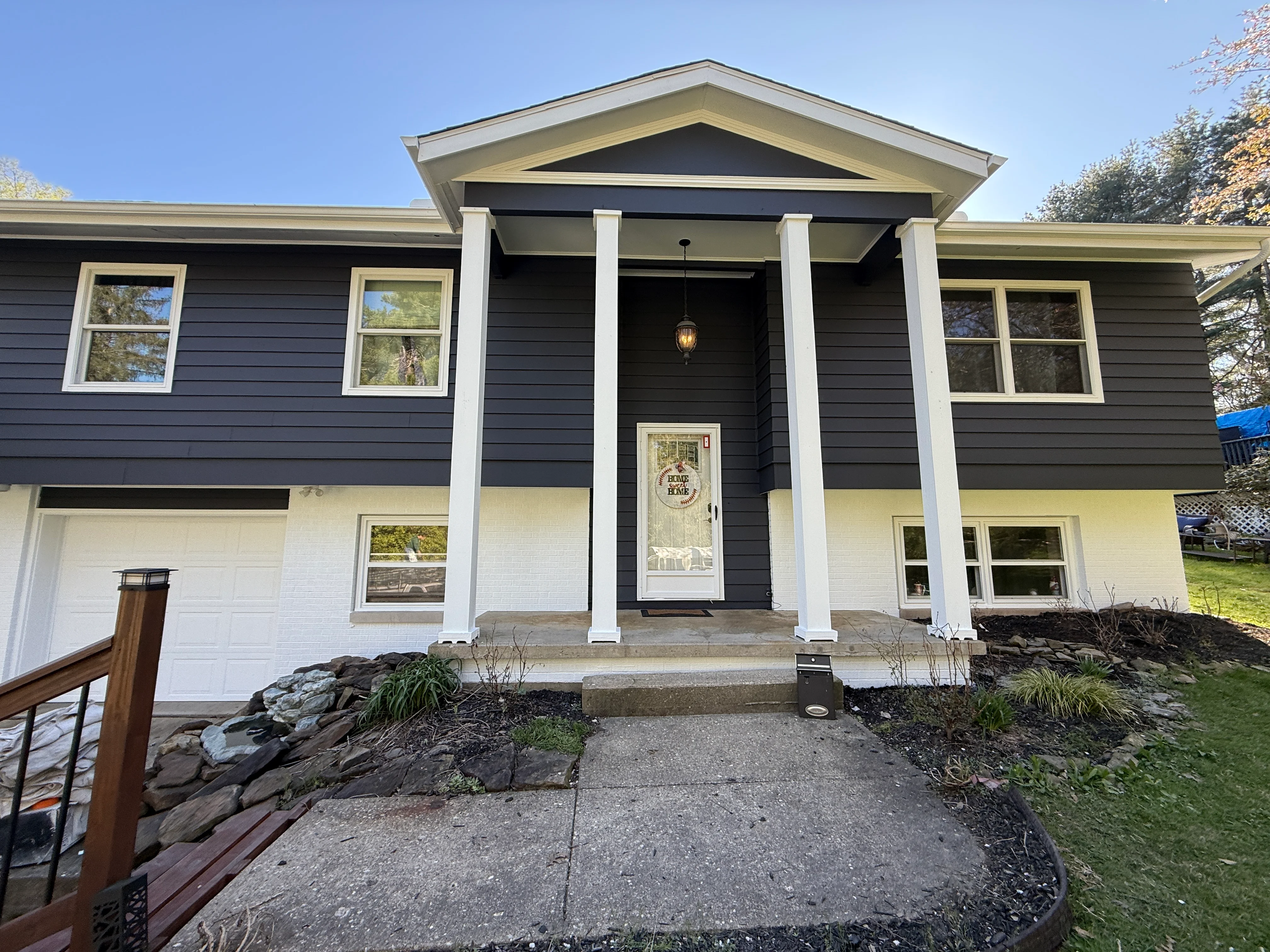 Dark blue and white painted split-level house with white trim and columns