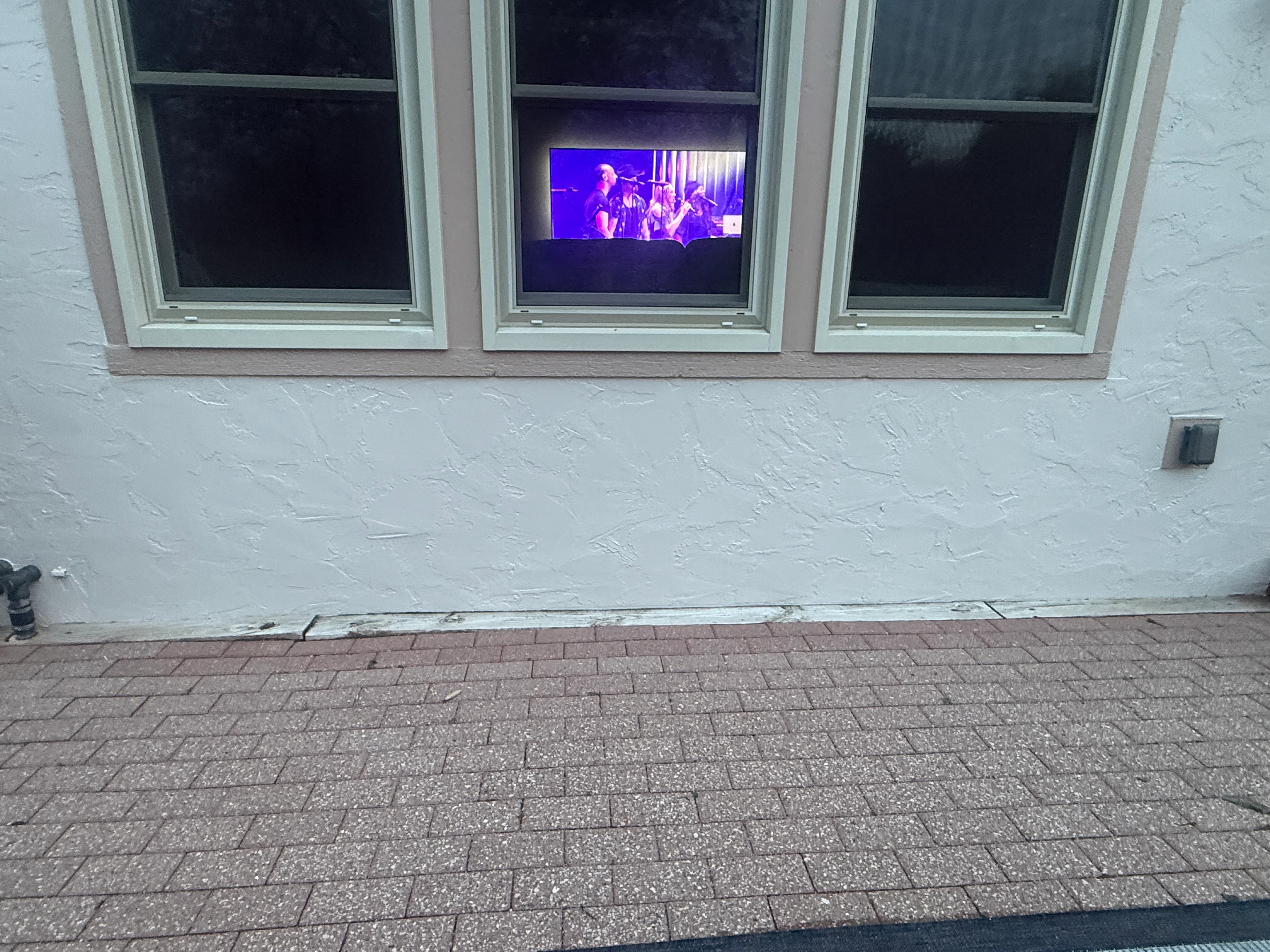 Freshly painted white textured exterior wall with three white-trimmed windows