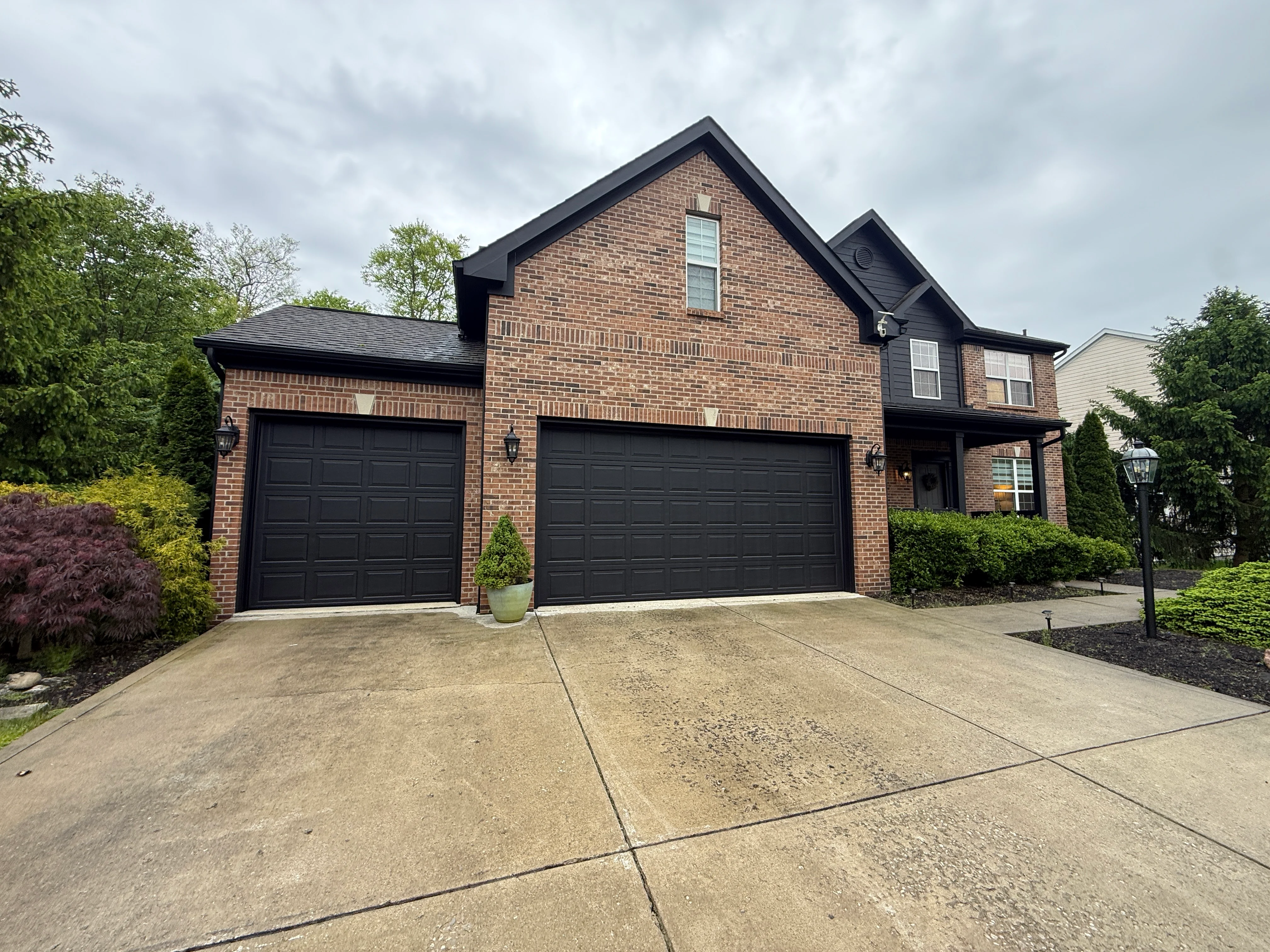 Two-story brick home with black painted garage doors and trim in New Albany