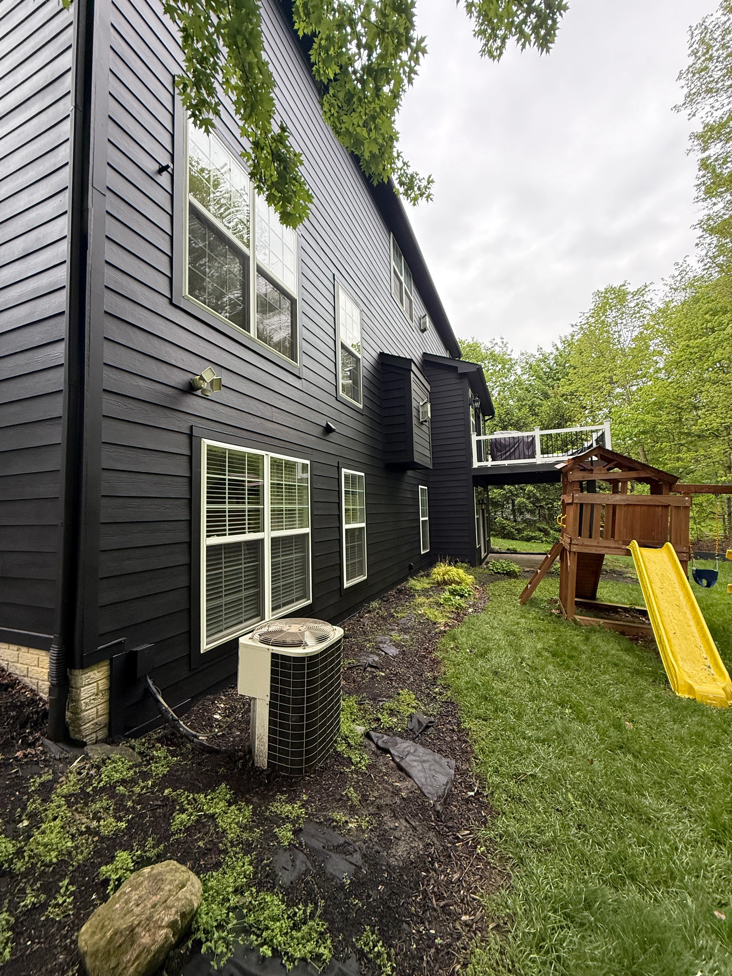 Black painted house exterior with white-trimmed windows and new siding installation