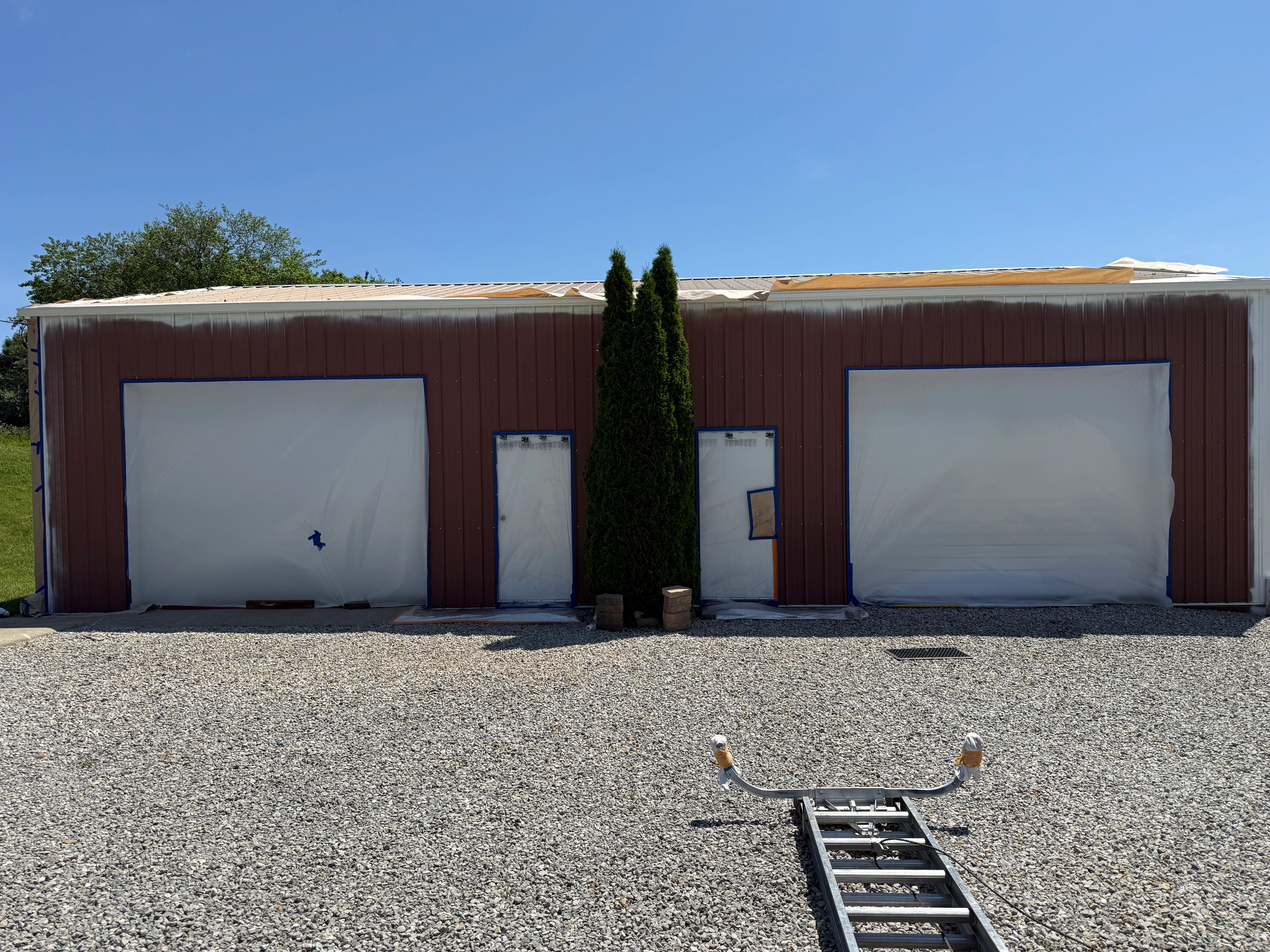 Burgundy metal commercial building with white garage doors and trim in New Albany