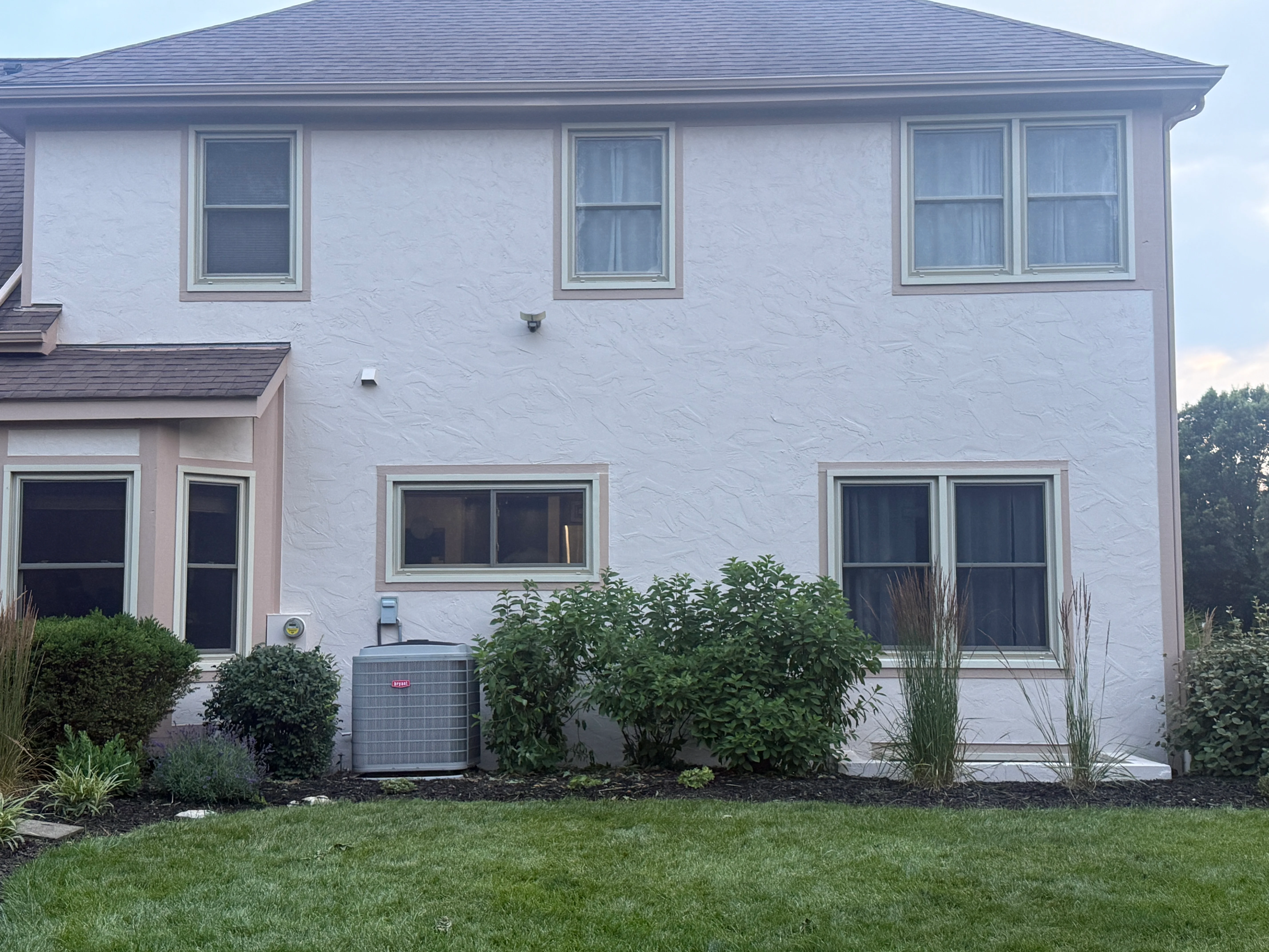 White two-story house with gray roof and trim, freshly painted exterior with landscaping