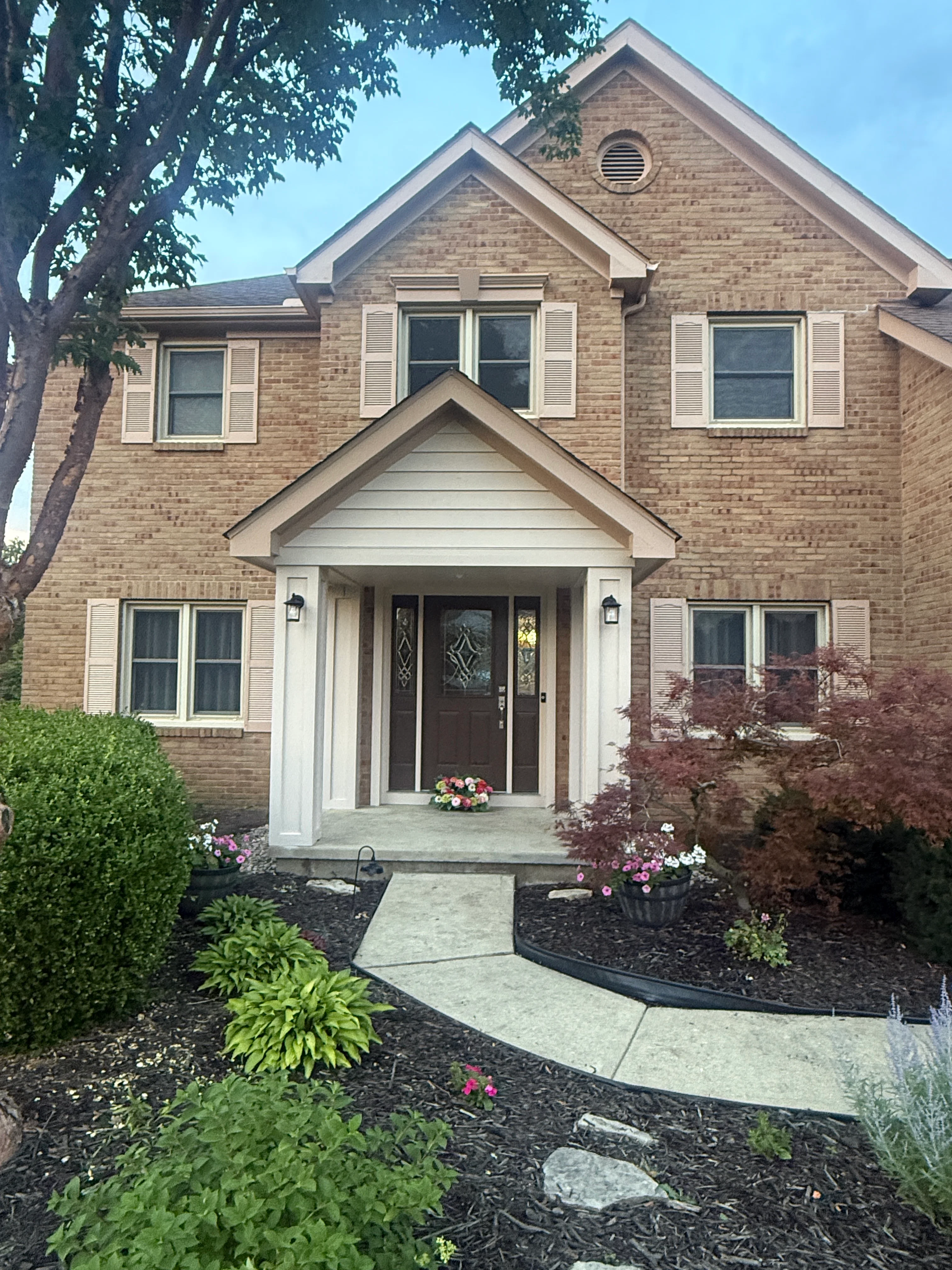 Two-story brick home with white painted trim, shutters, and entry portico in New Albany