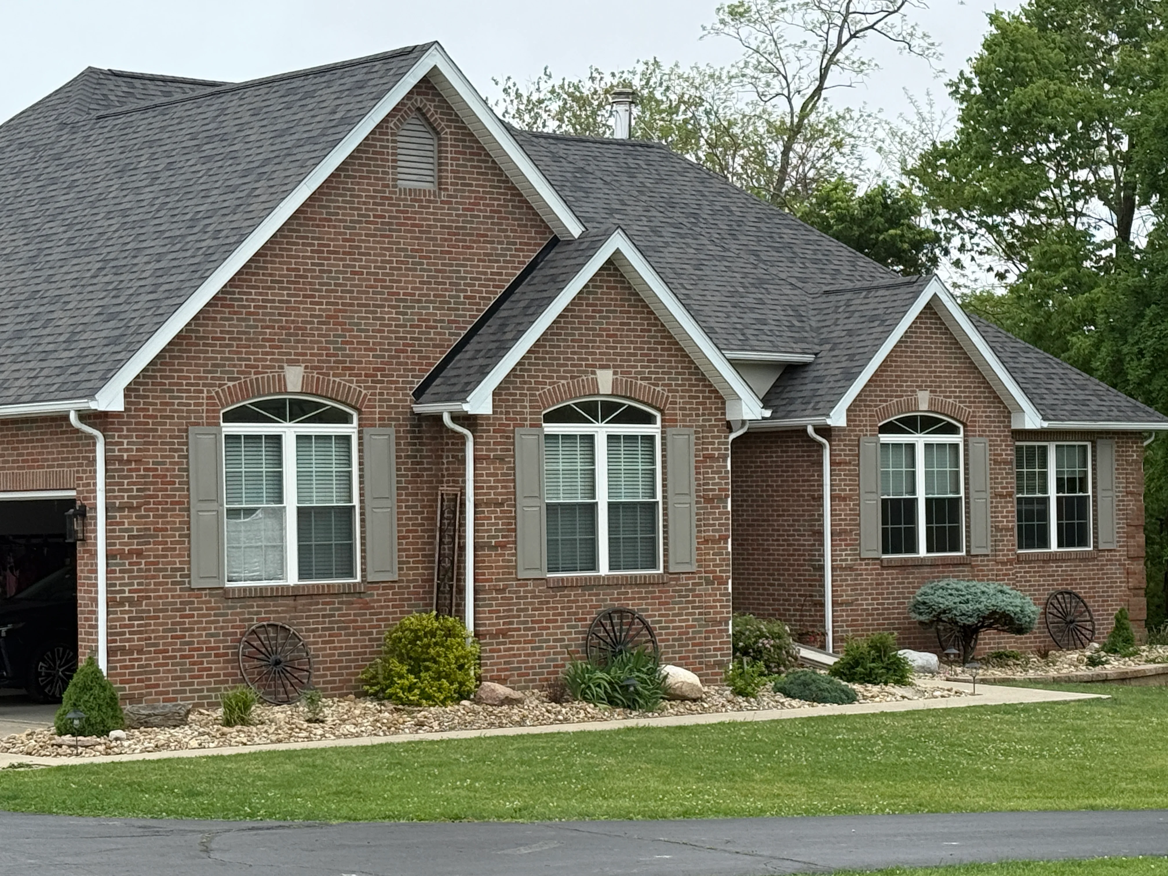 Brick home with white painted trim, shutters, and fascia around arched windows